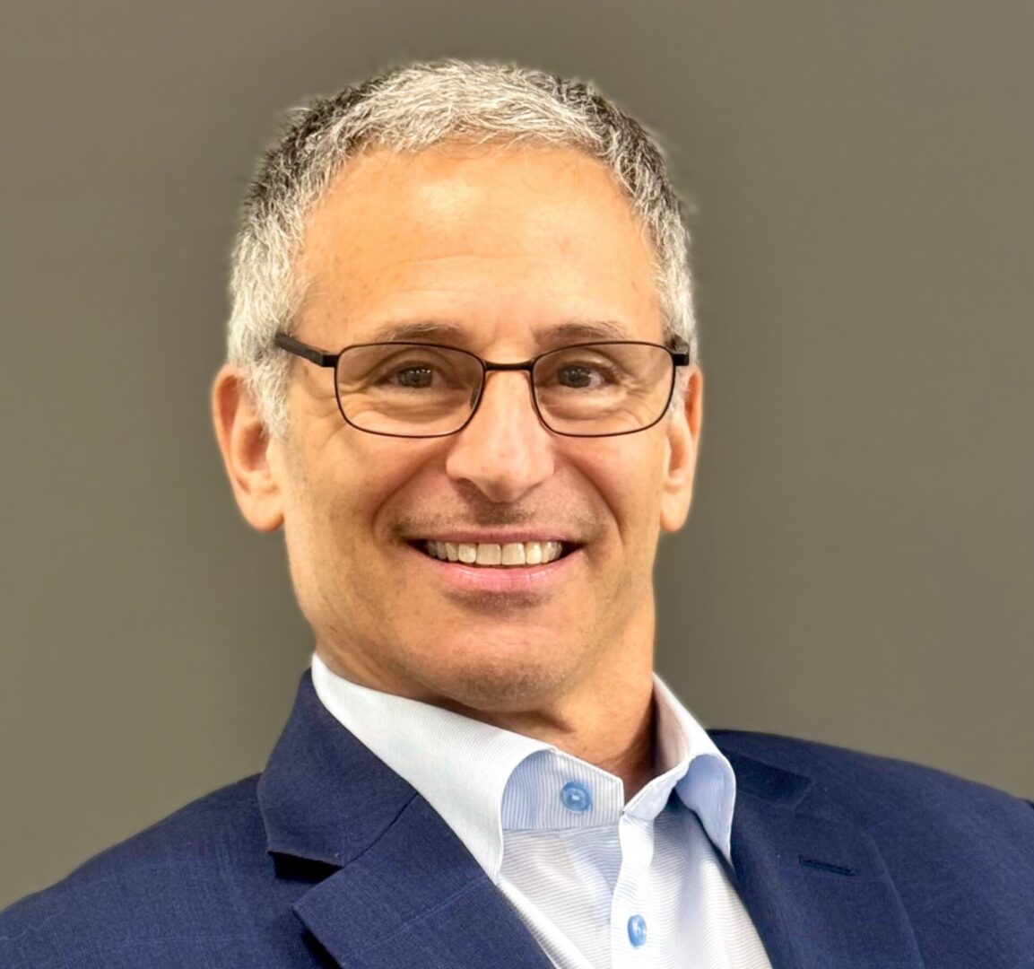 Smiling man in suit with glasses.