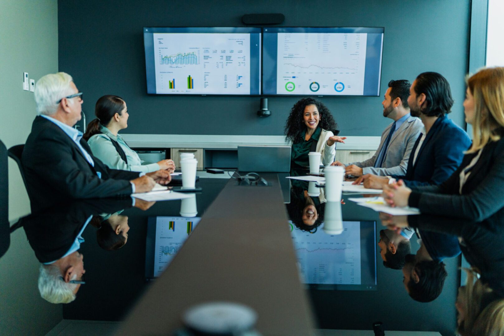 Business meeting with presentation screens in background.